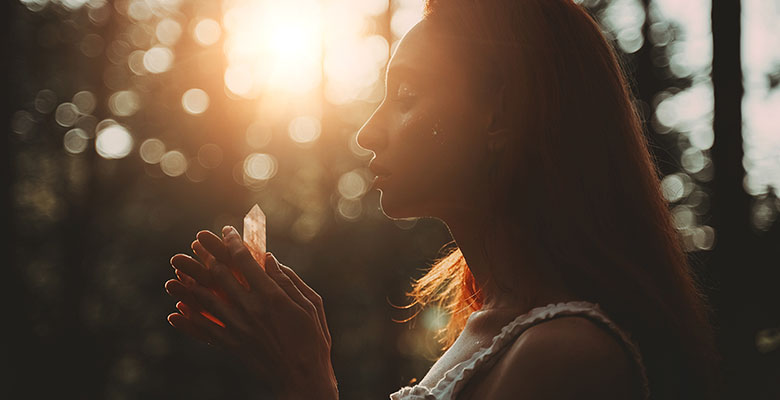 Mulher contra a luz do sol segurando um prisma de cristal