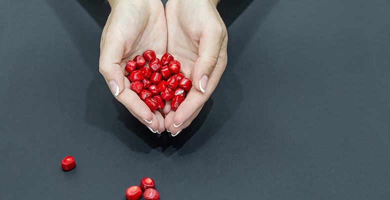 Mãos segurando contas de coral vermelho.