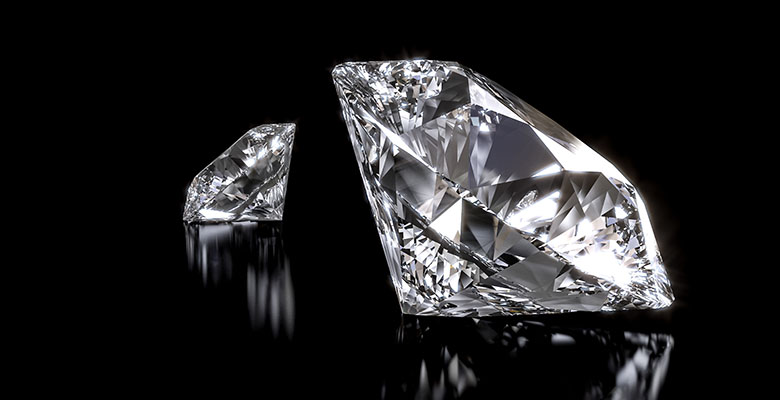 Dois diamantes exibidos lado a lado contrastando intensamente com o fundo preto que realça sua beleza. 