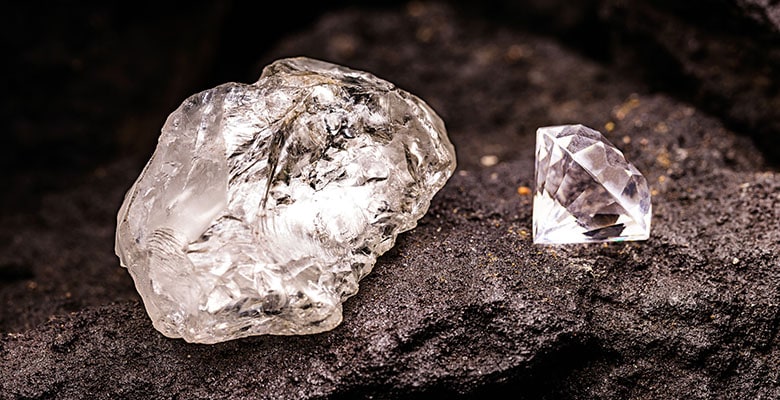 Rocha de diamante ao lado de um diamante, ambos posicionados sobre uma pedra