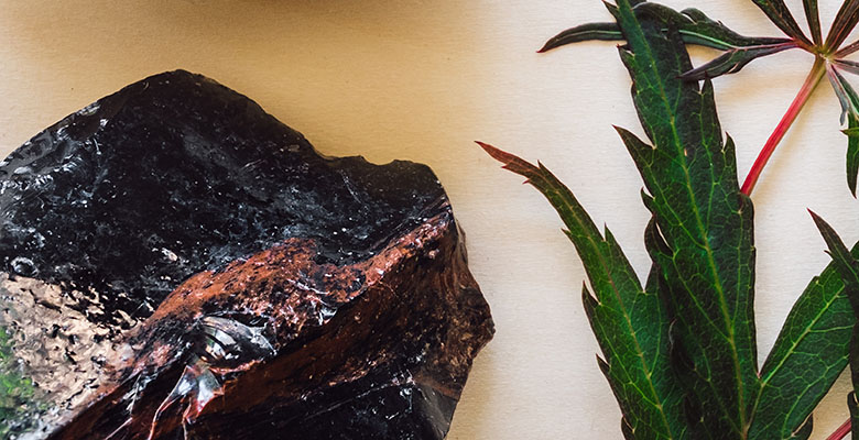 Pedra bruta de obsidiana mogno na mesa de madeira.