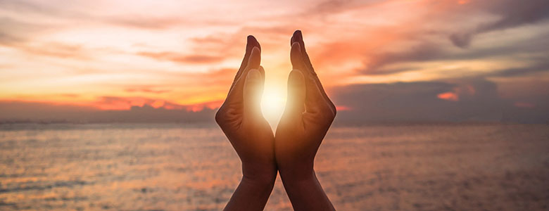 Duas mão envoltas no reflexo do sol