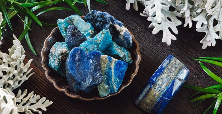 Pedras naturais brutas de lapis lazuli em cima de mesa com plantas