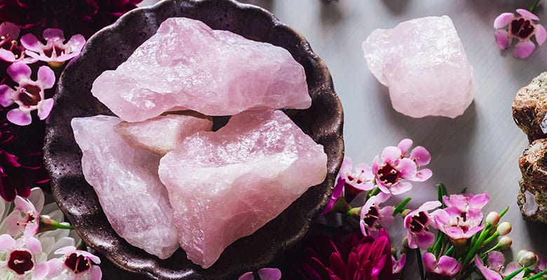 Pedra natural de quartzo rosa bruto em mesa com flores