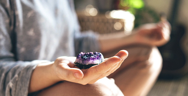 Mulher meditando com drusa de ametista natural na mão