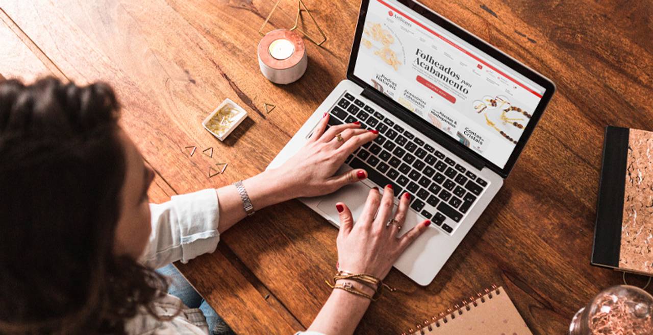 mulher navegando no site da artstones pelo notebook em mesa de madeira