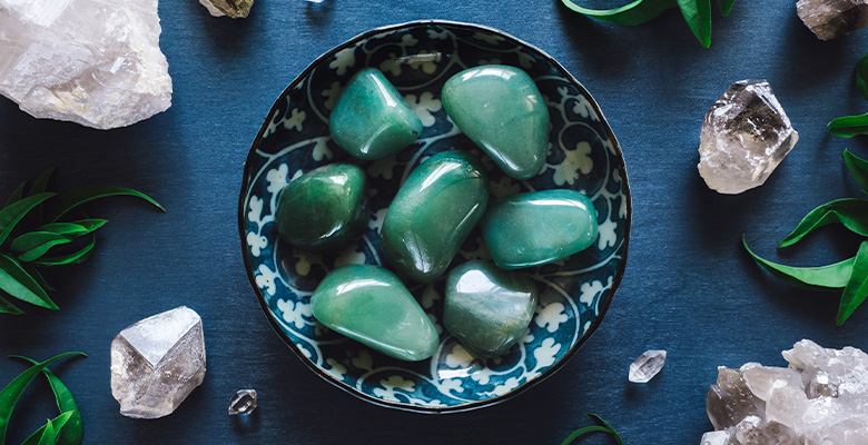 Pedras naturais de jade verde polido em mesa azul com cristais e plantas