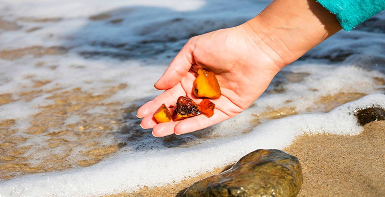mão segurando pedras de ambar natural na praia